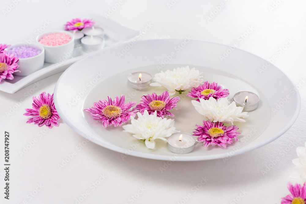 closeup shot of bath for nails with candles, flowers and colorful sea salt for manicure and pedicure at table in beauty salon