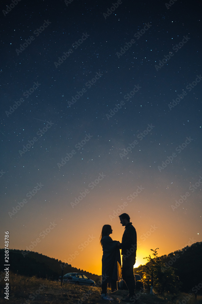 Silhouette of young couple under stars. The concept on the theme of love. romantic evening together, sunset, vertical photo