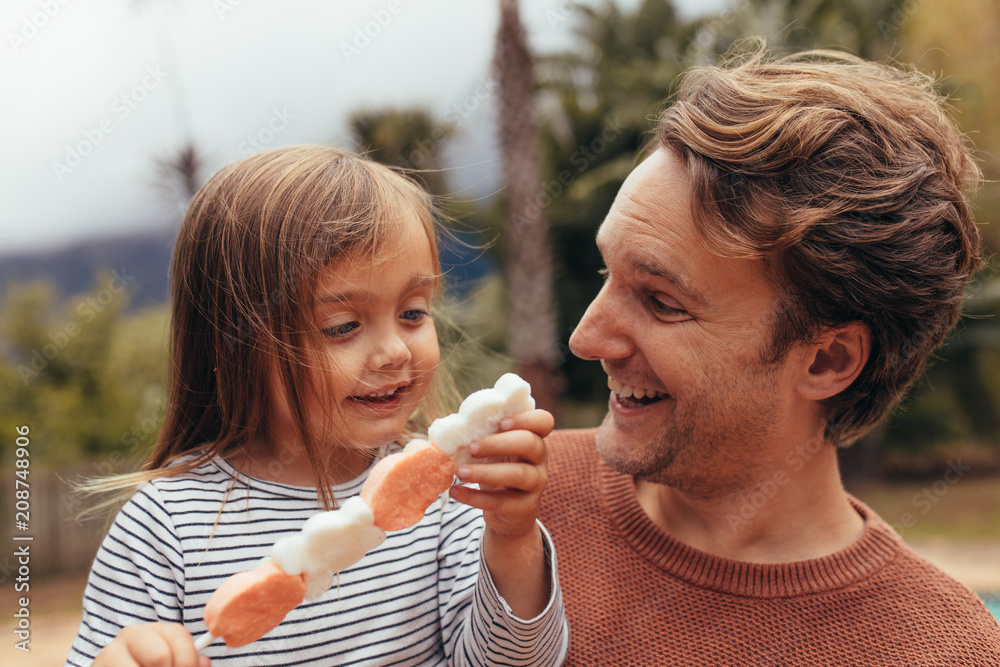 Obraz premium Little girl with her father outdoors holding a candy