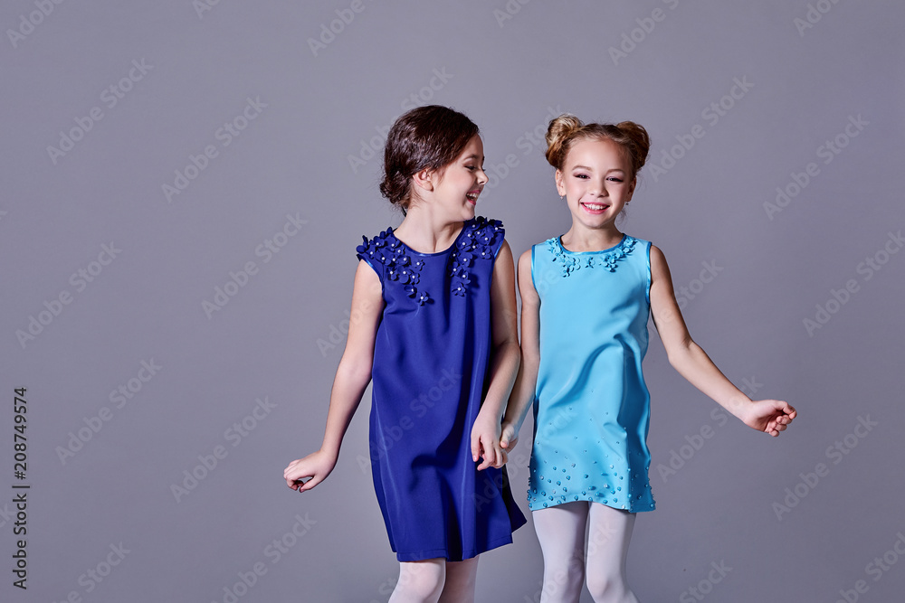 Fotka Two 2 little girls having fun in beautiful elegant dresses.Girlfriends fashion model children smile posing studio for catalog designer clothes. Classic lady style for kids teens. copy space. ze ...
