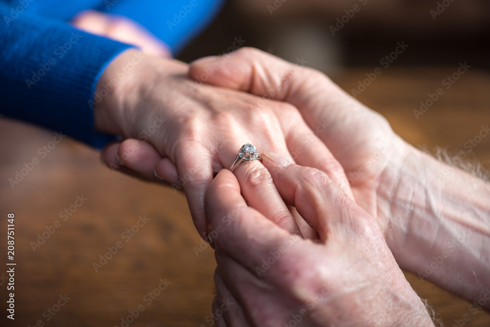 Man putting a ring on woman's finger