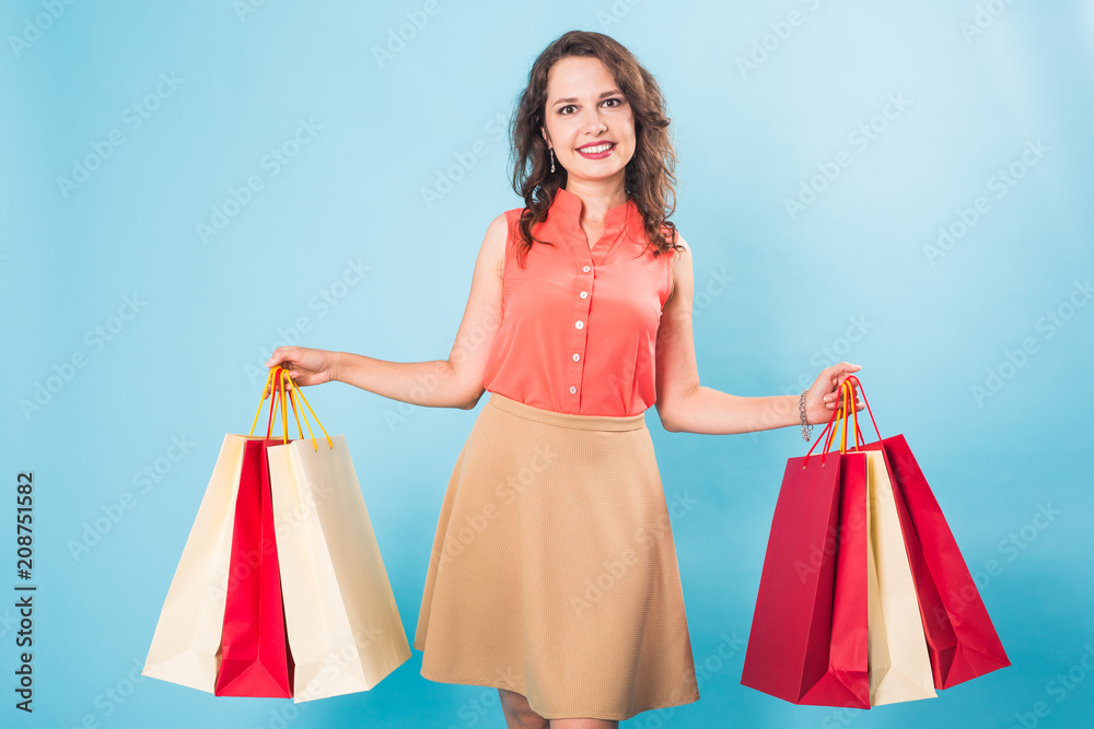 Young woman with shopping bags over blue background