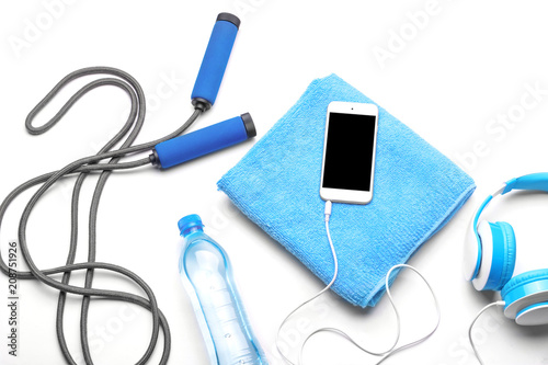 Composition with jump rope, bottle of water and mobile phone on white background