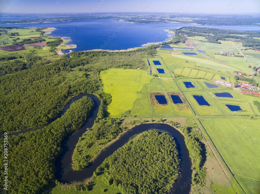 Meander of Wegorapa river flowing across wetlands, Mazury, Poland. Mamry Lake in the background Meander of Wegorapa river flowing across wetlands, Mazury, Poland. Mamry Lake in the background