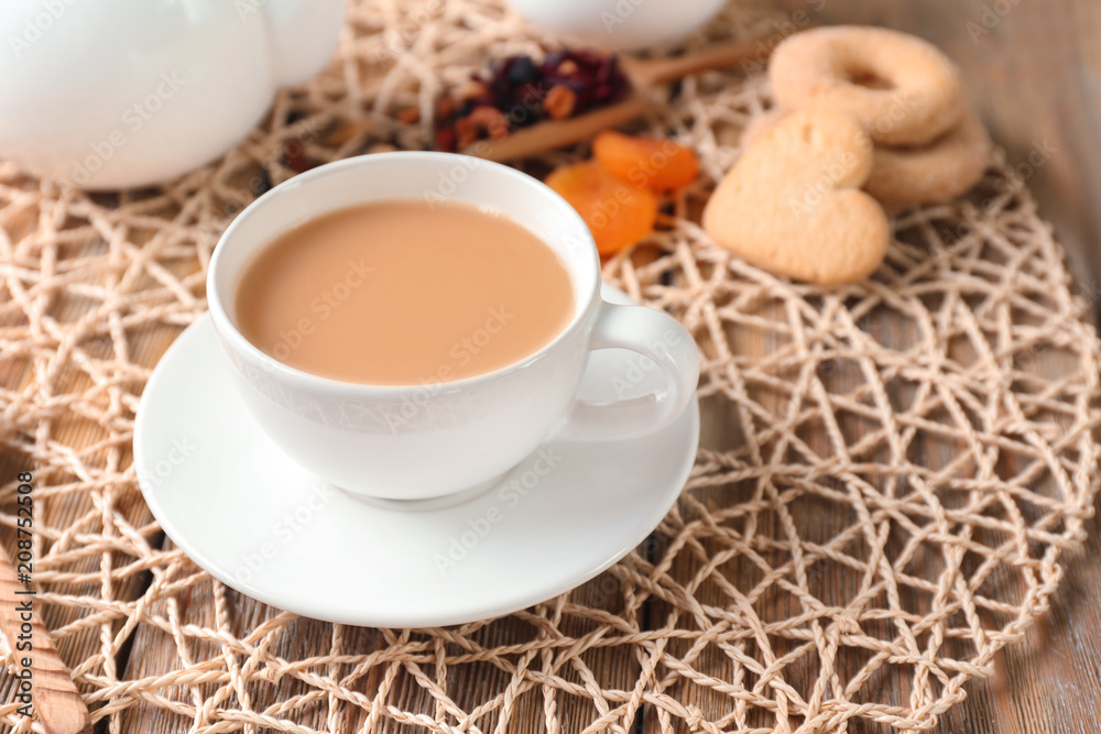Cup of aromatic tea with milk on wicker mat Cup of aromatic tea with milk on wicker mat
