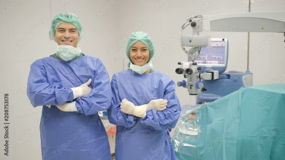 Portrait of Caucasian male ophtalmology surgeons and assistants wearing full surgical scrubs smiling to camera in operating theater at the hospital. Portrait of Caucasian male ophtalmology surgeons and assistants wearing full surgical scrubs smiling to camera in operating theater at the hospital.