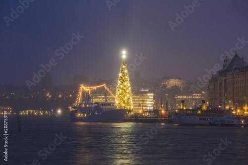 Beautiful winter scenery panorama of the Old Town (Gamla Stan) pier architecture with decorated gleaming Xmas Tree in Christmas and New Year holidays in Stockholm city, Night Sweden illuminated lights © Martin