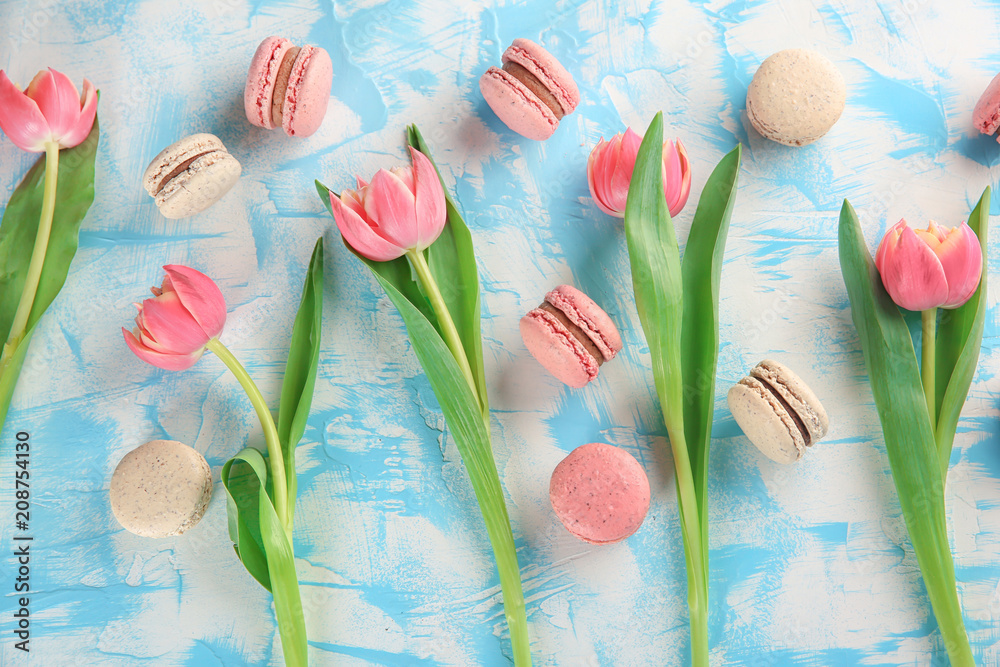 Flat lay composition with tasty macarons and tulips on color background