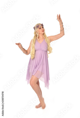 full length portrait of pretty blonde girl wearing purple fairy dress. standing pose, isolated on white studio background.