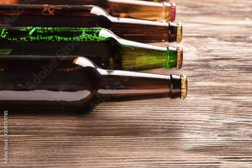 Glass bottles of beer on wooden background
