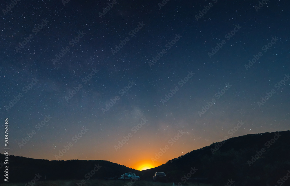 a beautiful view of the starry sky, and mountains, the sky full of stars, great panorama, in the foreground cars and a trailer for a boat