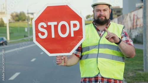 A construction road worker stopping traffic, holding a stop sign.
