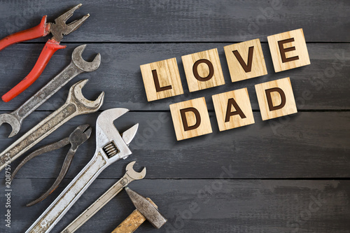 Love Dad inscription on wooden cubes with working tools on a wooden background.Happy fathers day concept. Greetings and gifts.