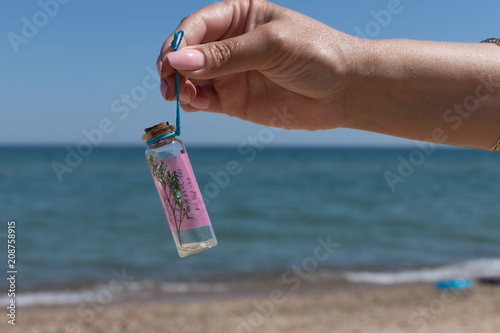 hand holding a bottle with desire on the background of a beautiful sea