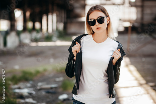 Girl wearing t-shirt and leather jacket posing against street , urban clothing style. Street photography