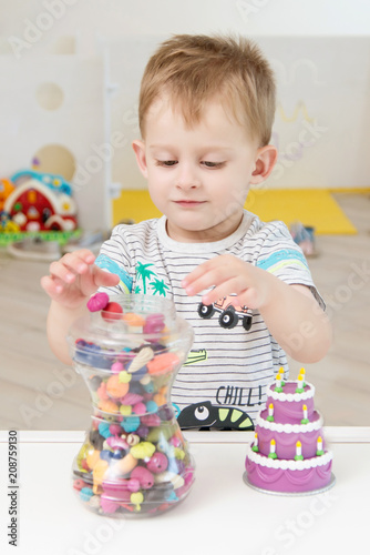 A little boy is playing with beads and other small toys. Pastime in the children garden or play center photo