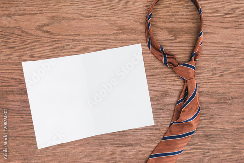 top view of tie and blank paper on wooden surface photo