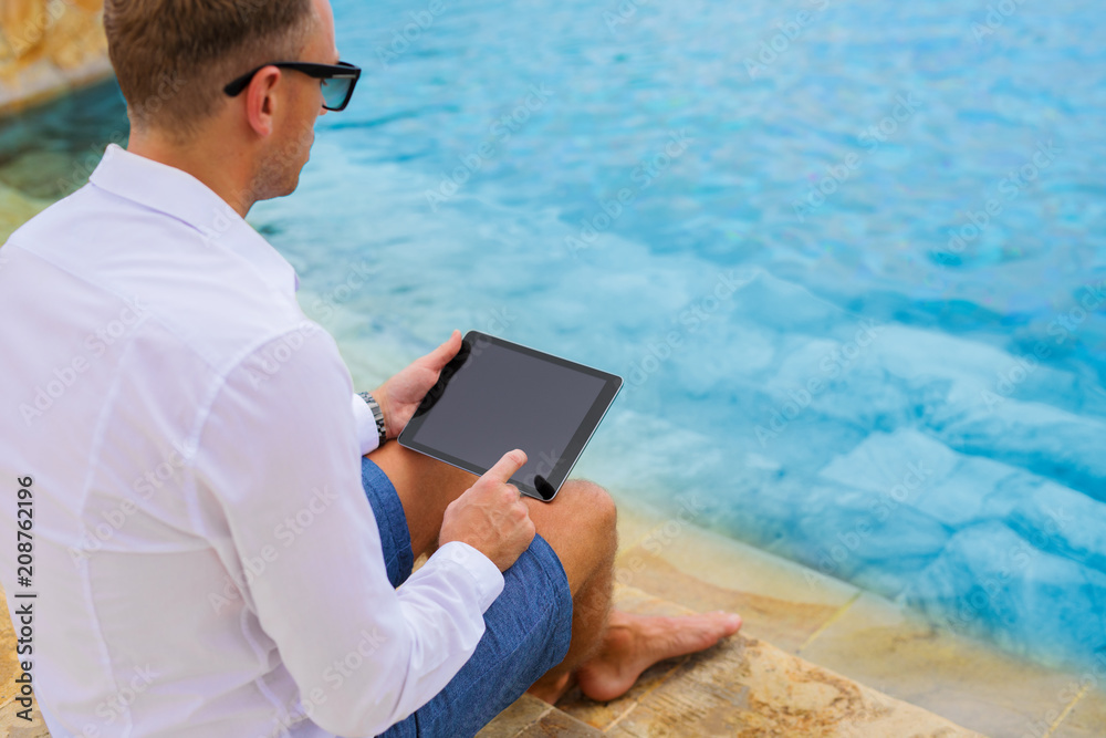 Business man using tablet by the pool