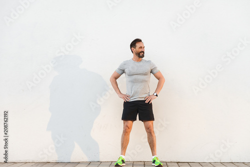 Smiling sportsman standing with arms on hips photo