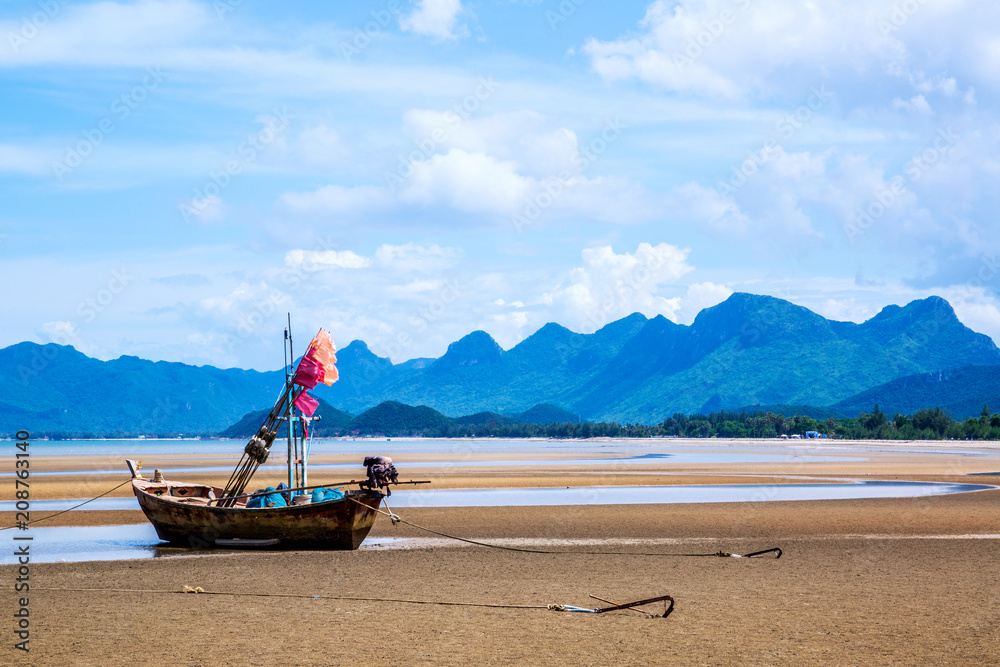 Small fishing boats on sand beach during low tide with cloudy blue sky at Pranburi Prachuap-Kirikhan Thailand Small fishing boats on sand beach during low tide with cloudy blue sky at Pranburi Prachuap-Kirikhan Thailand
