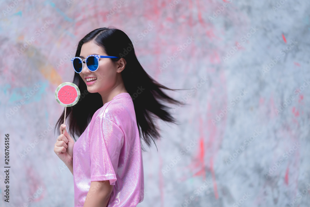 Obraz premium Woman with lollipop candy wearing pink fashion dress on colorful background.