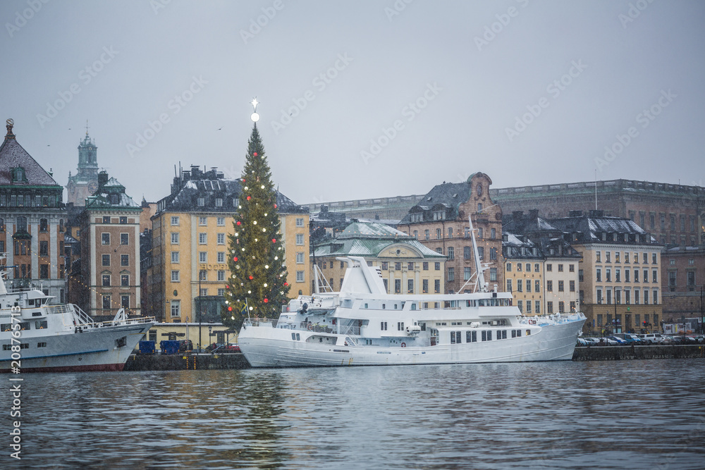 Beautiful winter scenery panorama of the Old Town (Gamla Stan) pier architecture with decorated gleaming Xmas Tree the largest in the world in Christmas and New Year holidays in Stockholm city, Sweden