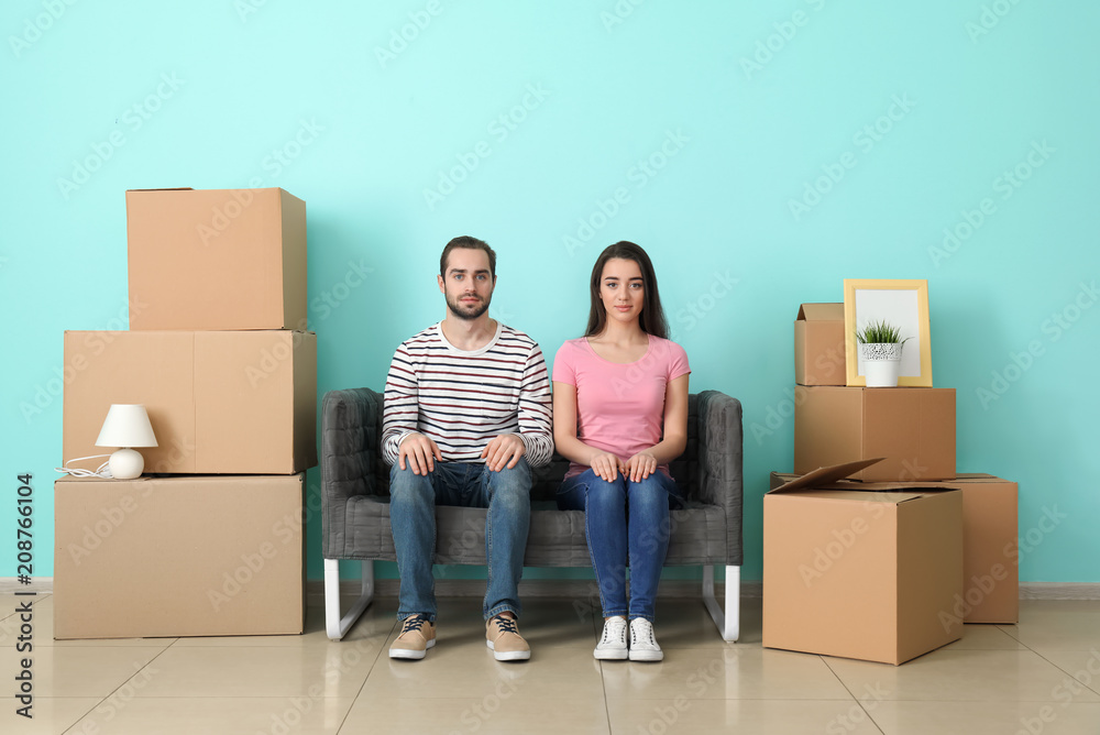 Young couple resting on sofa near boxes indoors. Moving into new house Young couple resting on sofa near boxes indoors. Moving into new house