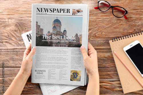 Woman reading morning newspaper at wooden table