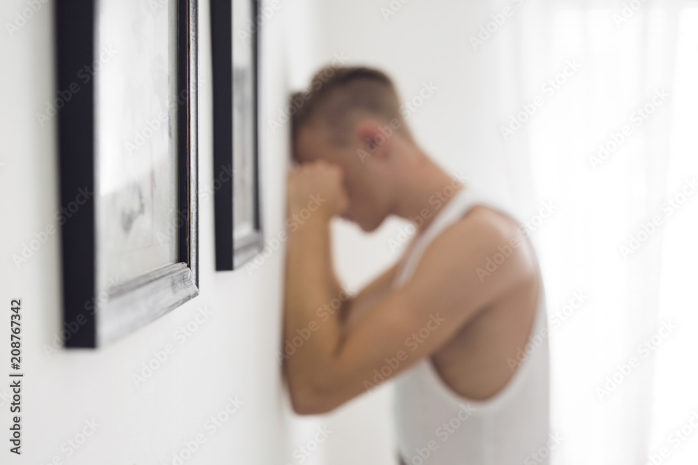 Pensive young man with face against wall Pensive young man with face against wall