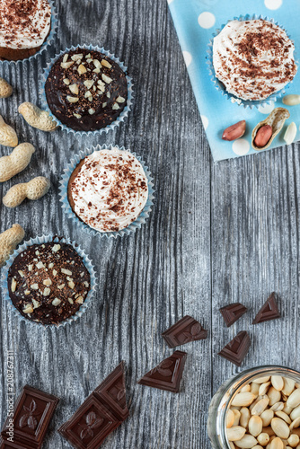 Tasty chocolate cupcakes on a grey wooden background with chocolate and nuts