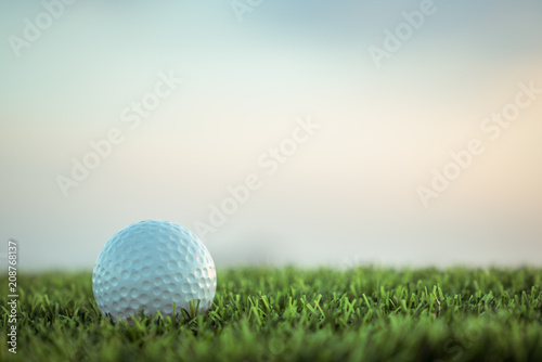 Golf ball on grass on sky background