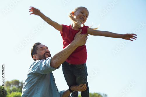 Wonderful childhood. Alert bearded father smiling while having fun with his little daughter