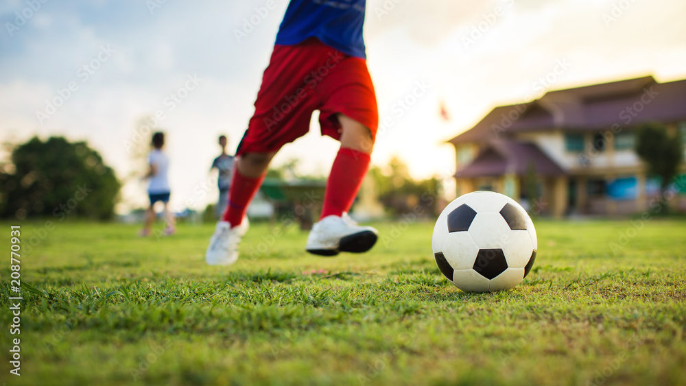 action sport picture of a group of kids playing soccer football for exercise in community rural area under the sunset.