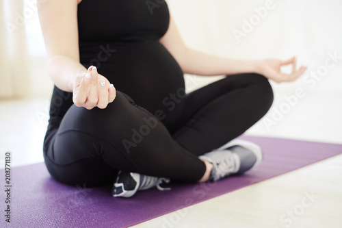 Close up view of young pregnant woman doing morning yoga exercis