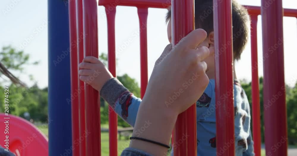 Mother and toddler son playing on play structure - holding bars - slow motion Mother and toddler son playing on play structure - holding bars - slow motion