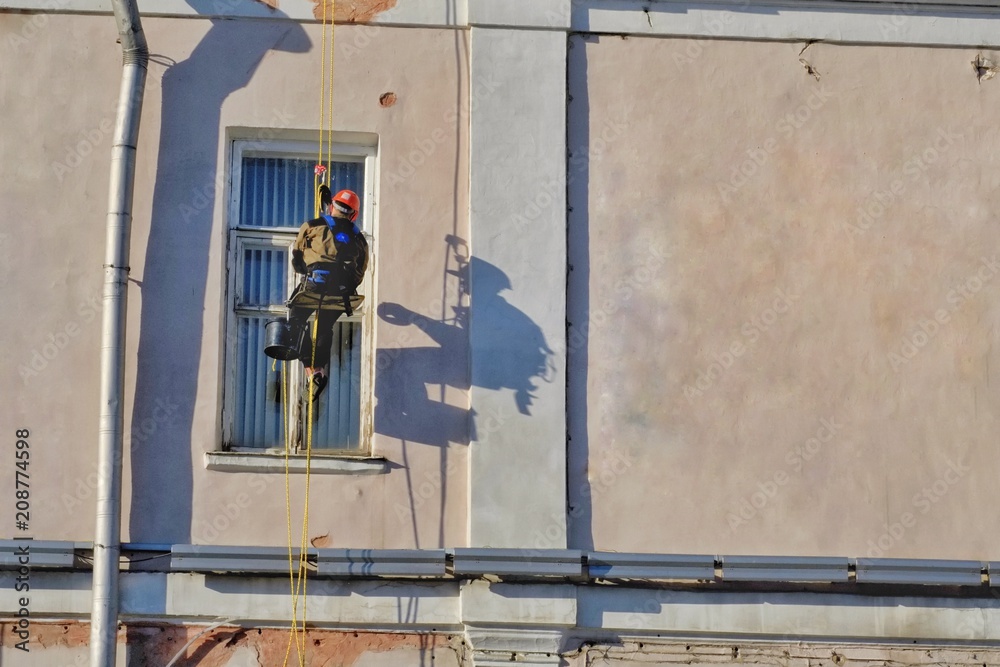 The man worker climbing at construction site with helmet and uniform for works at height outside building. The man worker climbing at construction site with helmet and uniform for works at height outside building.