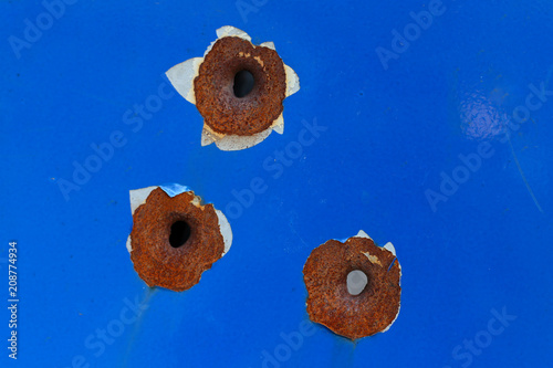 Holes from bullets on blue metal. photo