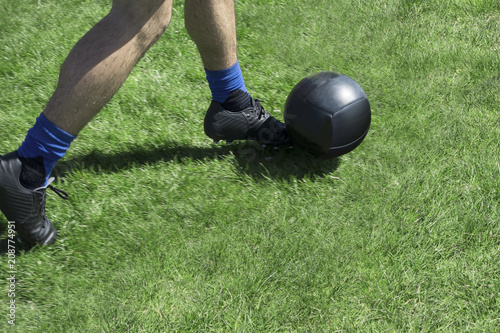 soccor player kicking abll of a green grassy field with black kelletts and balck ball