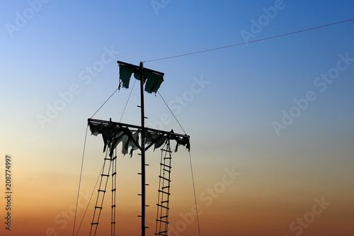 Old sailer pirate ship, with torn sails, at sunset.