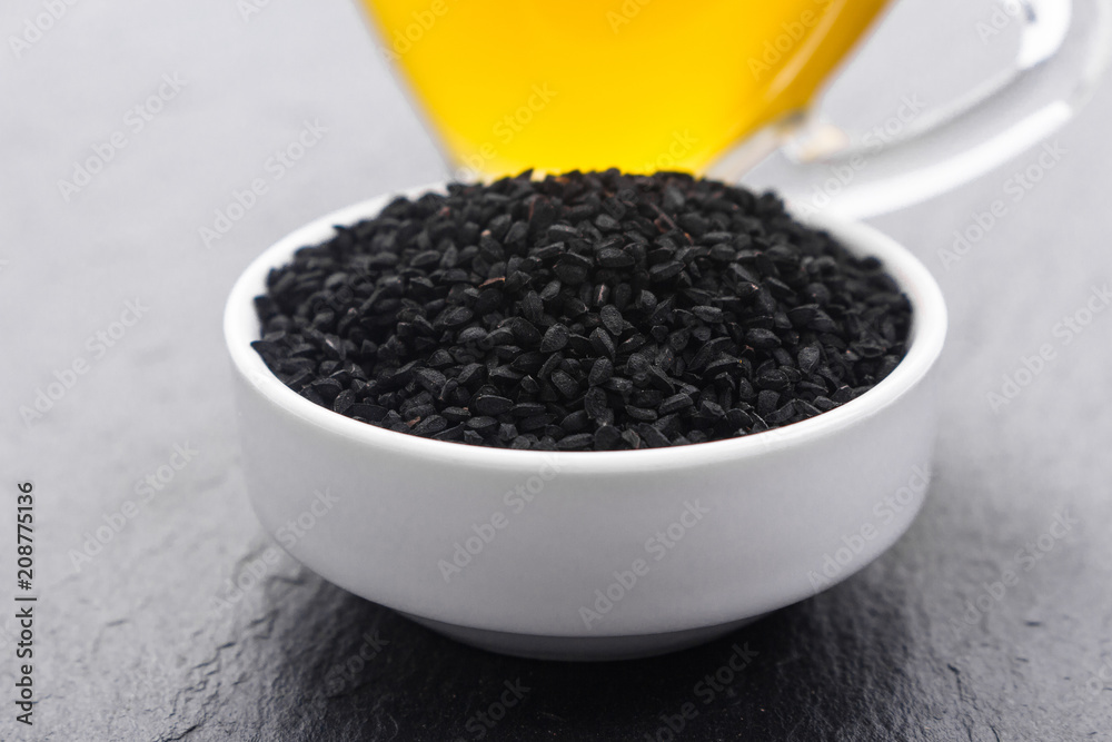 grains of black cumin and oil on the rustic background grains of black cumin and oil on the rustic background