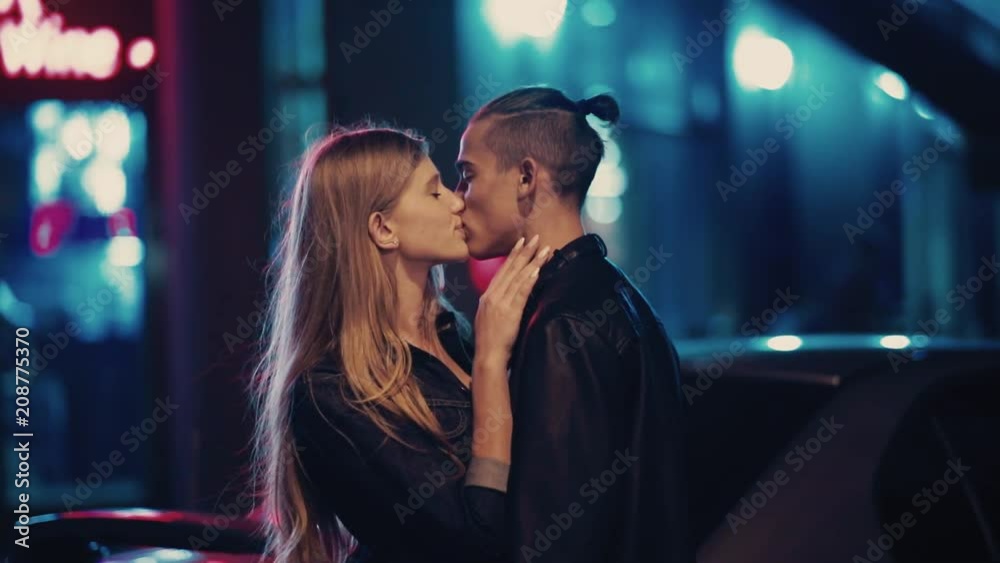 Close up portrait of beautiful young couple kissing at night city street at colorful lights background. Love story, romantic atmosphere, true feelings. Happy together. Close up portrait of beautiful young couple kissing at night city street at colorful lights background. Love story, romantic atmosphere, true feelings. Happy together.