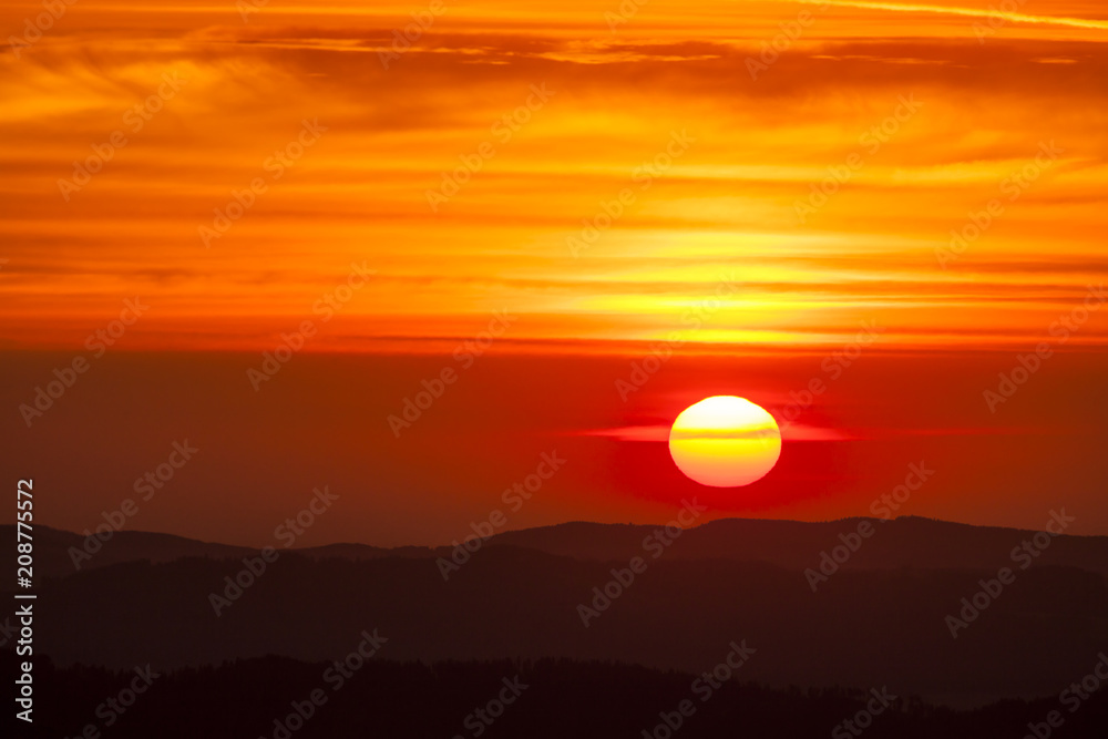 Natural Sunset Sunrise Scene Over highland or mountains. Bright Dramatic Sky And Dark Ground. Countryside Landscape Under Scenic Colorful Sky At Daybreak Dawn. Sun Over Skyline, Horizon. Warm Colors.