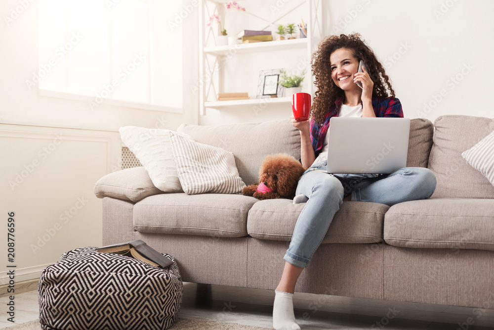 Smiling young woman with mobile, laptop and little dog at home Smiling young woman with mobile, laptop and little dog at home