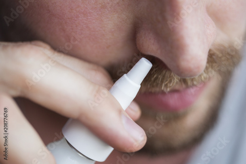 Close-up of man using nasal spray