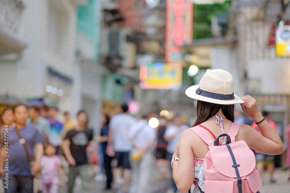 Young Woman traveling backpacker with hat, Asian traveler standing on Senado Square street, landmark and popular for tourist attractions in Macau. Travel concept