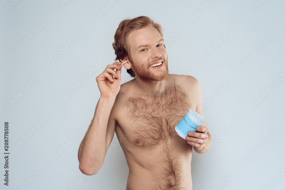 Fototapeta premium Young happy man is cleaning ears with cotton swab.
