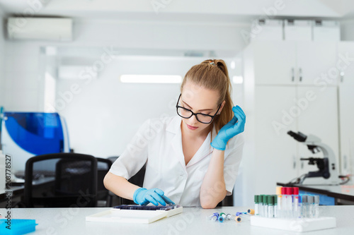Scientist analyzing microscope slide at laboratory. Female Working in Laboratory With Microscope. Researcher examining slide. Concenrated doctor working with microscope in laboratory