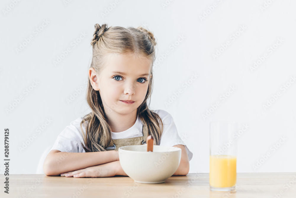 confident little schoolgirl sitting at table with breakfast isolated on white confident little schoolgirl sitting at table with breakfast isolated on white