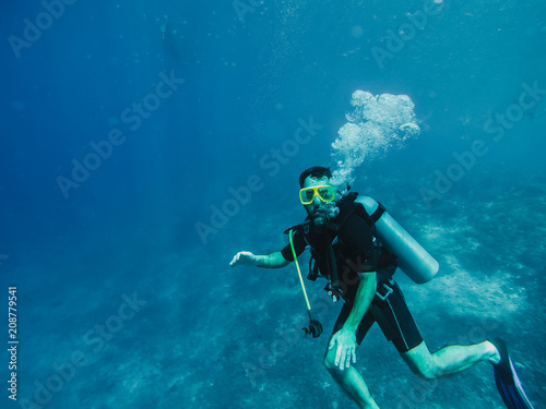 .Young tourist diving in the Gili island, Indonesia, many meters deep, discovering the wild life of the seabed. Lifestyle and travel concept.