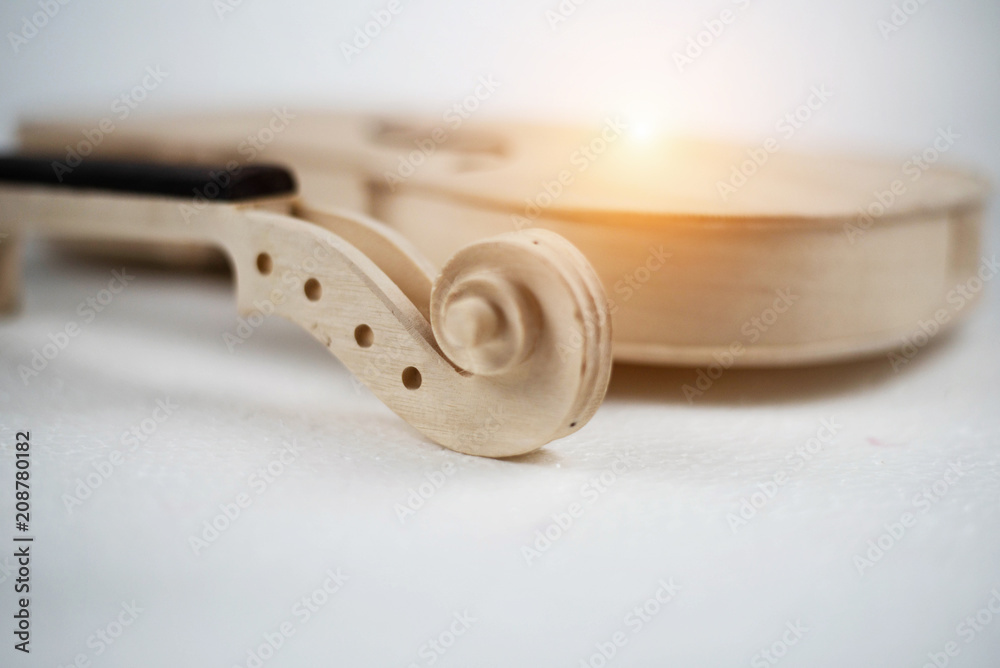 In selective focus of raw violin neck and scroll with peghole.blurry lightdesign background. In selective focus of raw violin neck and scroll with peghole.blurry lightdesign background.